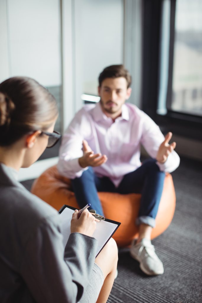 Unhappy man consulting counselor during therapy
